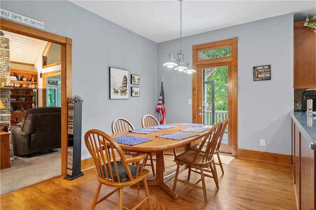 dining area with vaulted ceiling, an inviting chandelier, and light hardwood / wood-style floors