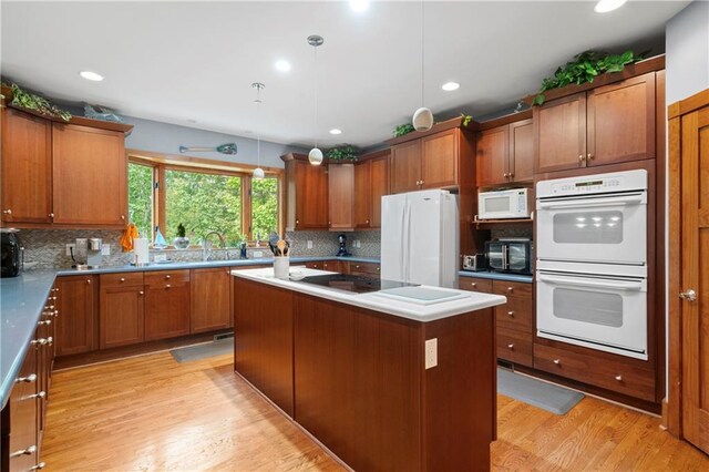 kitchen with pendant lighting, light hardwood / wood-style flooring, a kitchen island, and black appliances