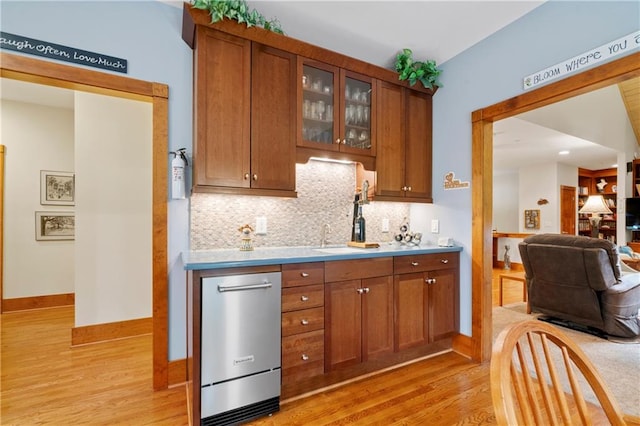 kitchen featuring tasteful backsplash, dishwasher, and light wood-type flooring