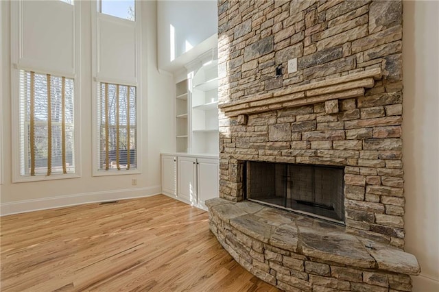 unfurnished living room with a stone fireplace and light wood-type flooring