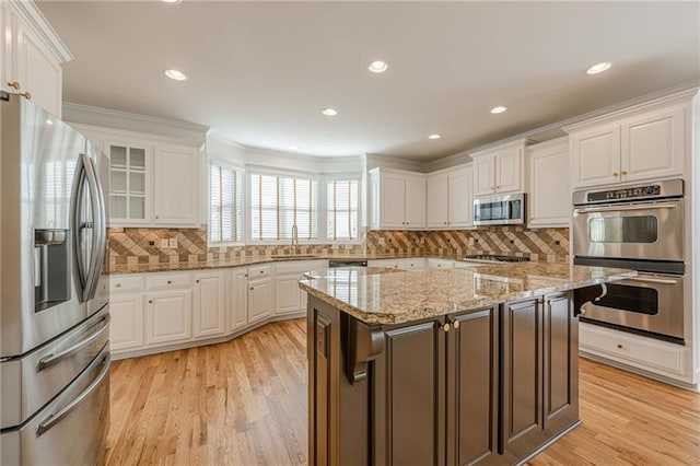 kitchen featuring light stone countertops, appliances with stainless steel finishes, a center island, and white cabinets