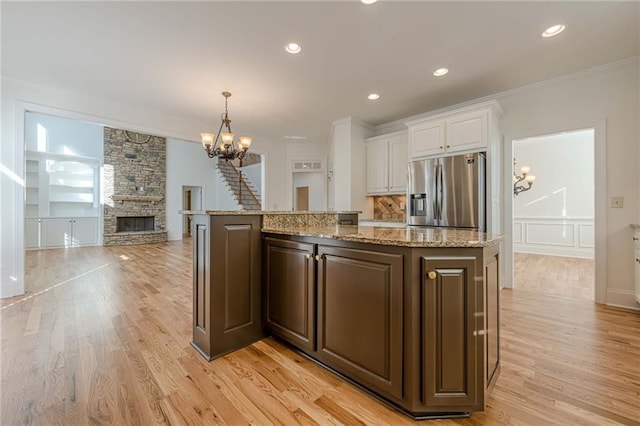 kitchen with dark brown cabinetry, a chandelier, stainless steel fridge, a kitchen island, and white cabinets