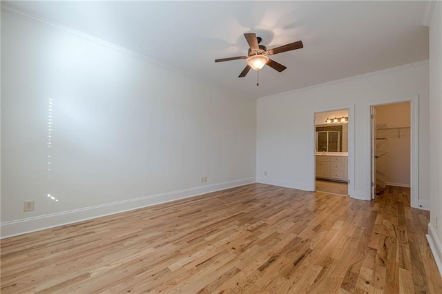 unfurnished bedroom with ensuite bathroom, crown molding, a walk in closet, light wood-type flooring, and ceiling fan