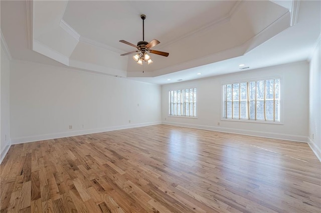 spare room featuring ceiling fan, ornamental molding, a raised ceiling, and light wood-type flooring