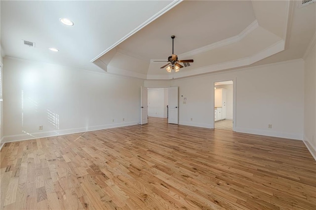 empty room featuring crown molding, a tray ceiling, light hardwood / wood-style floors, and ceiling fan