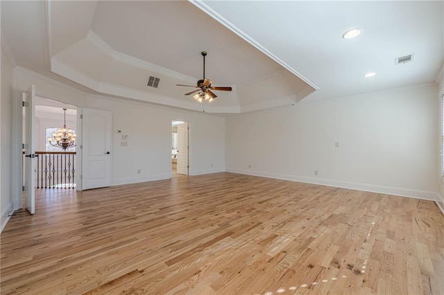 unfurnished living room featuring crown molding, ceiling fan with notable chandelier, light wood-type flooring, and a tray ceiling