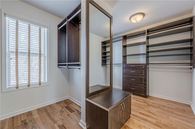 walk in closet with light hardwood / wood-style flooring