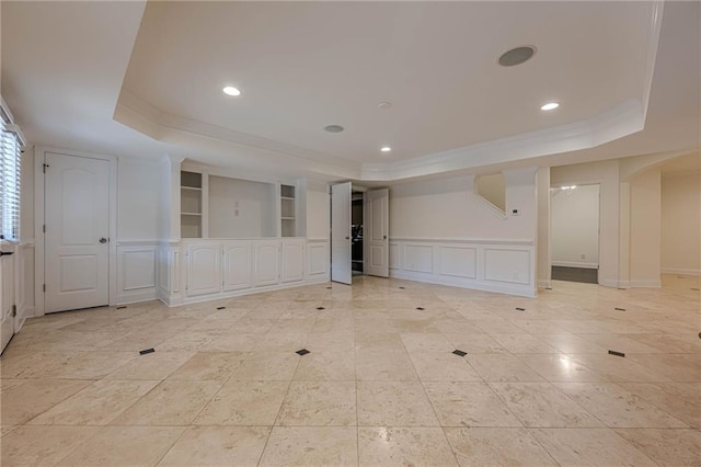 empty room featuring light tile patterned floors, a tray ceiling, ornamental molding, and built in shelves