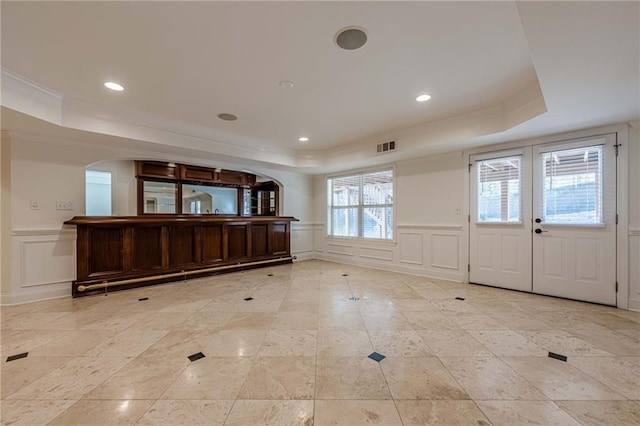 foyer with crown molding, a tray ceiling, and french doors