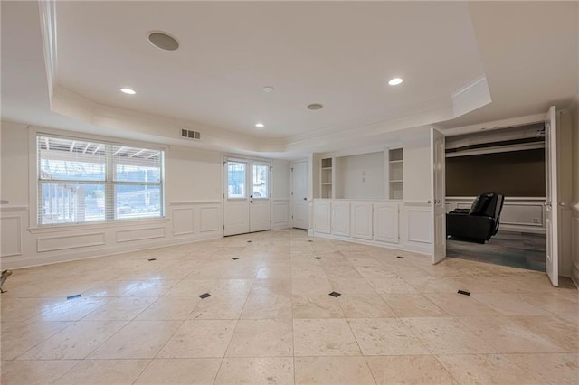 spare room featuring ornamental molding, a tray ceiling, and built in features