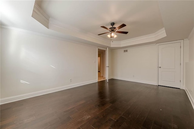 spare room with crown molding, a tray ceiling, dark hardwood / wood-style floors, and ceiling fan