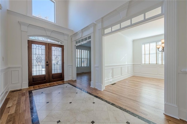 entryway with an inviting chandelier, light hardwood / wood-style flooring, french doors, and a high ceiling