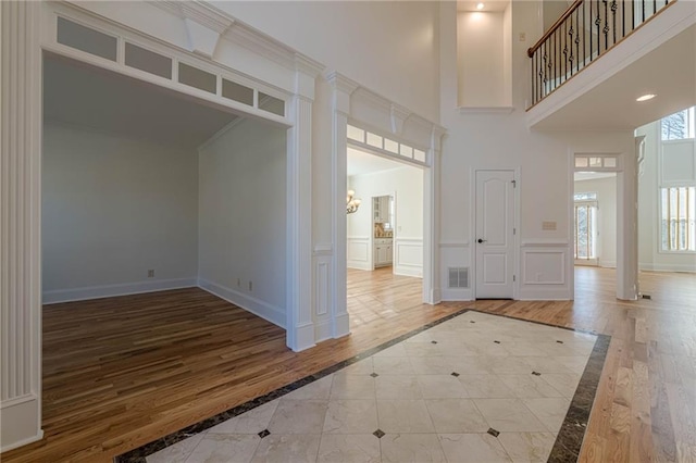 foyer entrance with a high ceiling, ornamental molding, and hardwood / wood-style floors