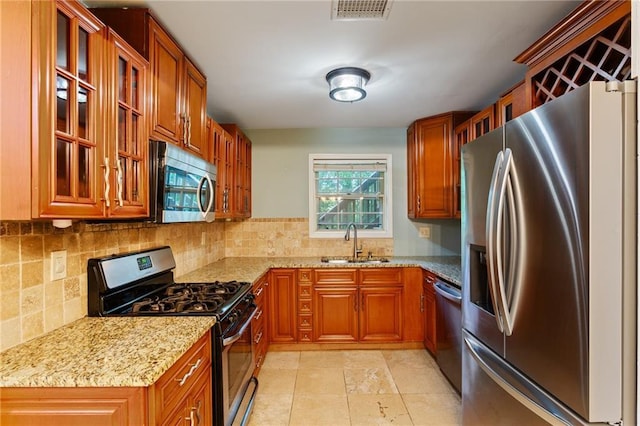 602 Country Park Dr SE, Smyrna, GA 30080 - kitchen featuring appliances with stainless steel finishes, a sink, light stone countertops, tasteful backsplash, and brown cabinetry