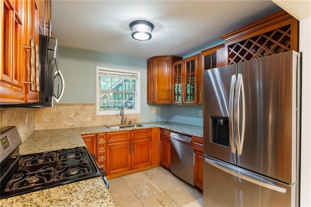 602 Country Park Dr SE, Smyrna, GA 30080 - kitchen featuring appliances with stainless steel finishes, a sink, brown cabinets, light stone countertops, and glass insert cabinets