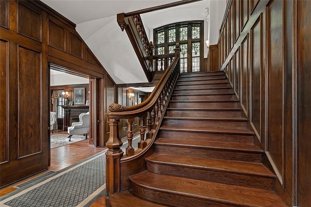 staircase featuring a fireplace, wood walls, and wood finished floors