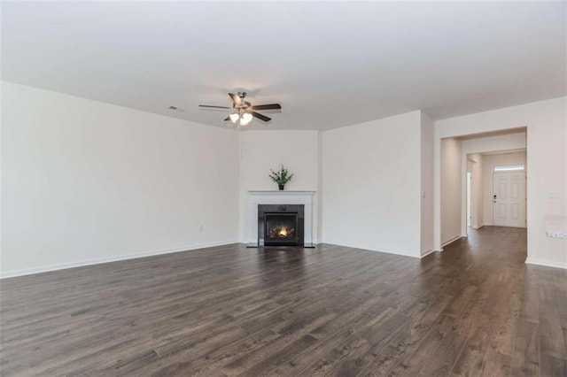 977 Daurian Dr, Statham, GA 30666 - unfurnished living room featuring dark wood-style flooring, ceiling fan, and a warm lit fireplace
