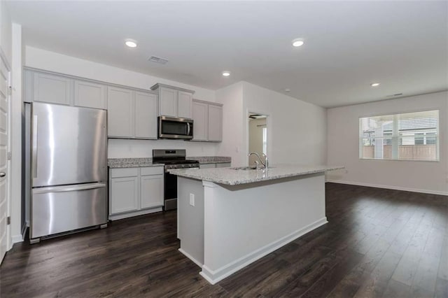 977 Daurian Dr, Statham, GA 30666 - kitchen with stainless steel appliances, dark wood-style floors, light stone counters, an island with sink, and recessed lighting