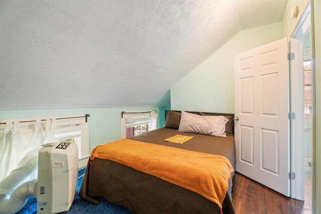 bedroom with vaulted ceiling, dark wood-type flooring, multiple windows, and a textured ceiling