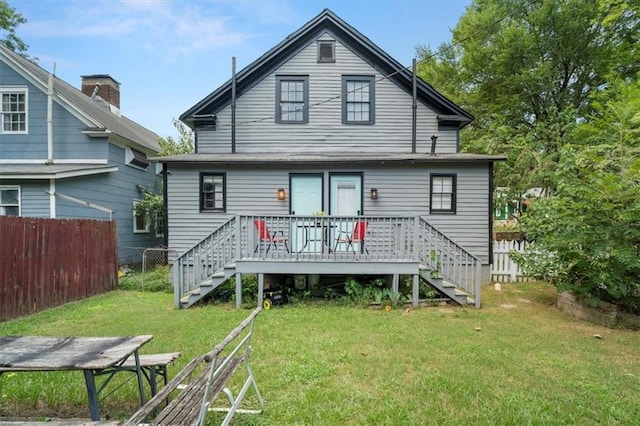 rear view of house with a wooden deck and a lawn