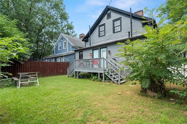 rear view of house featuring a wooden deck and a yard