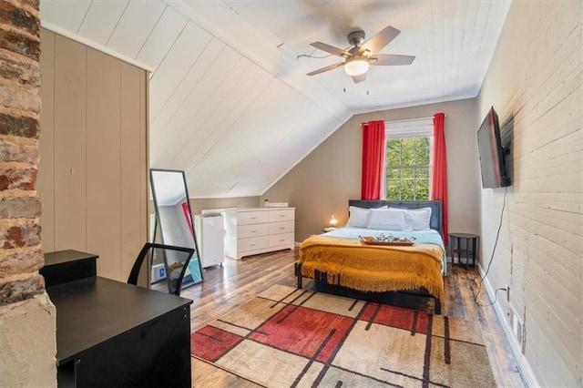 bedroom with ceiling fan, hardwood / wood-style floors, and vaulted ceiling