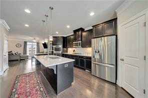 kitchen featuring appliances with stainless steel finishes, a breakfast bar, an island with sink, hanging light fixtures, and crown molding