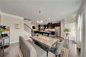 dining area with crown molding, dark wood-type flooring, and an inviting chandelier