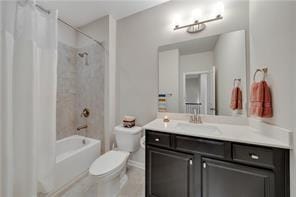 full bathroom with vanity, shower / tub combo, and toilet