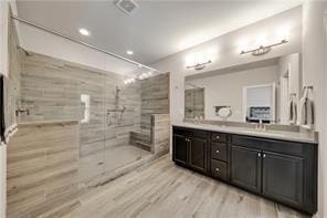 bathroom with vanity, hardwood / wood-style flooring, and tiled shower