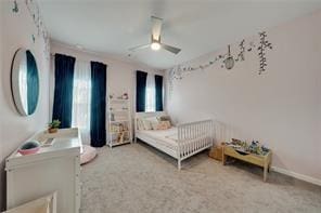 bedroom with a nursery area, ceiling fan, and carpet