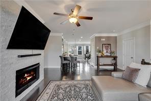 living room with crown molding, ceiling fan, and a fireplace