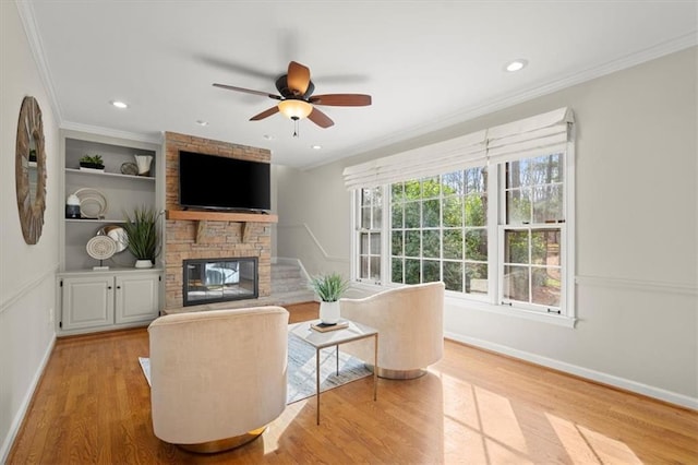 living room featuring ornamental molding, a fireplace, and light hardwood / wood-style floors