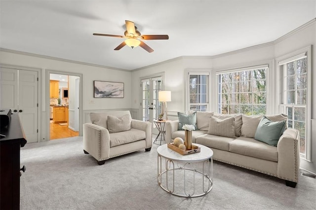 carpeted living room featuring crown molding, french doors, and ceiling fan