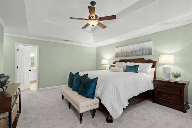 carpeted bedroom featuring a raised ceiling, crown molding, connected bathroom, and ceiling fan