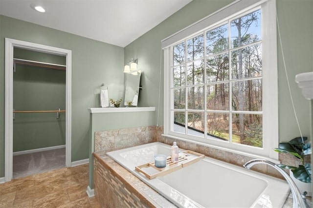 bathroom featuring a relaxing tiled tub and a wealth of natural light