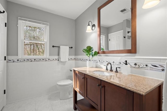 bathroom featuring vanity, tile walls, tile patterned floors, and toilet