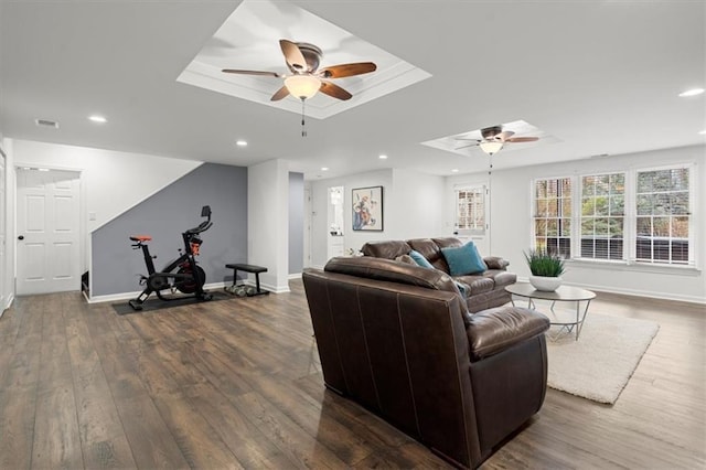 living room featuring ceiling fan, dark hardwood / wood-style flooring, and a tray ceiling