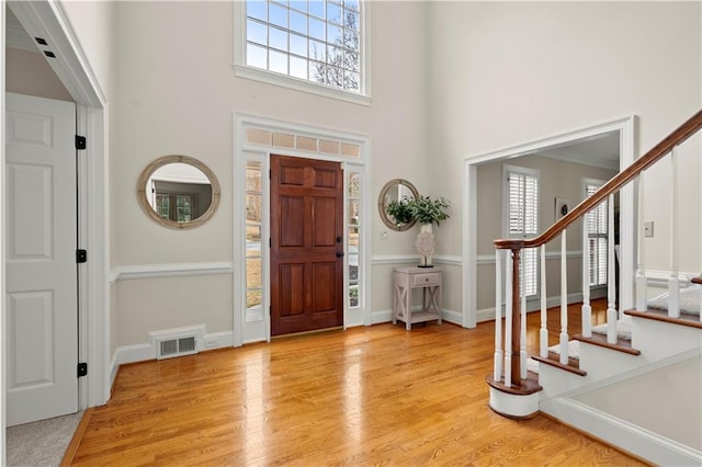 entrance foyer with a towering ceiling, plenty of natural light, and light hardwood / wood-style floors