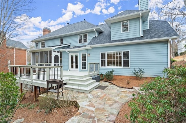 back of property with a wooden deck, a sunroom, and a patio