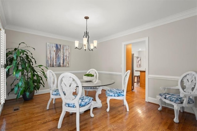 dining area with crown molding, hardwood / wood-style flooring, and a chandelier