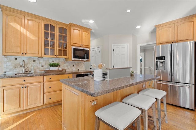 kitchen featuring built in microwave, sink, a center island, stainless steel fridge with ice dispenser, and dark stone countertops