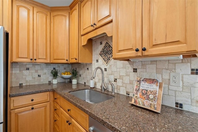 kitchen with tasteful backsplash, dark stone counters, and sink