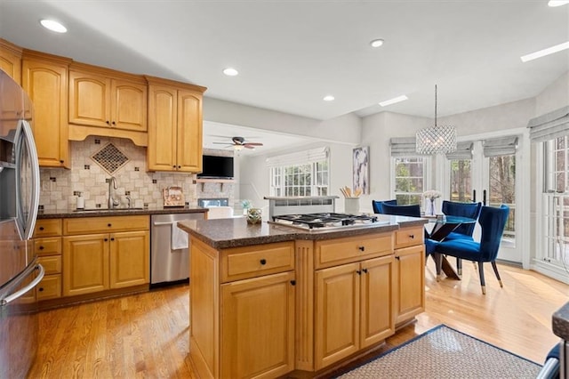 kitchen with a kitchen island, pendant lighting, sink, light hardwood / wood-style floors, and stainless steel appliances