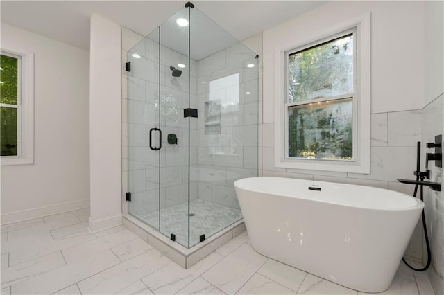 full bathroom with a freestanding tub, baseboards, marble finish floor, and a shower stall