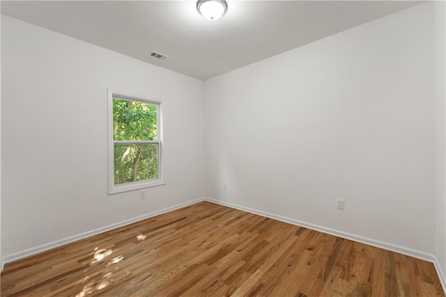 unfurnished room with visible vents, baseboards, and wood finished floors