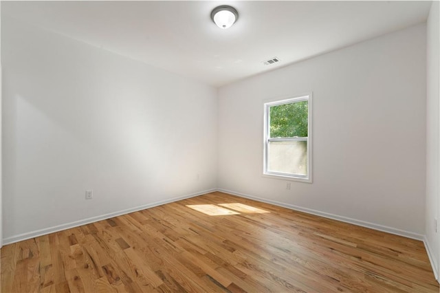 unfurnished room featuring light wood-style floors, visible vents, and baseboards