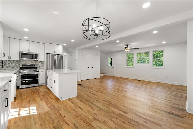 kitchen with backsplash, a center island, light wood-style floors, appliances with stainless steel finishes, and light countertops