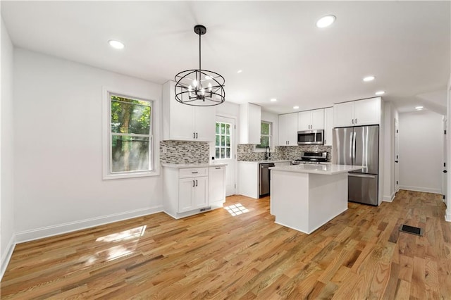 kitchen with decorative backsplash, light countertops, white cabinets, and stainless steel appliances