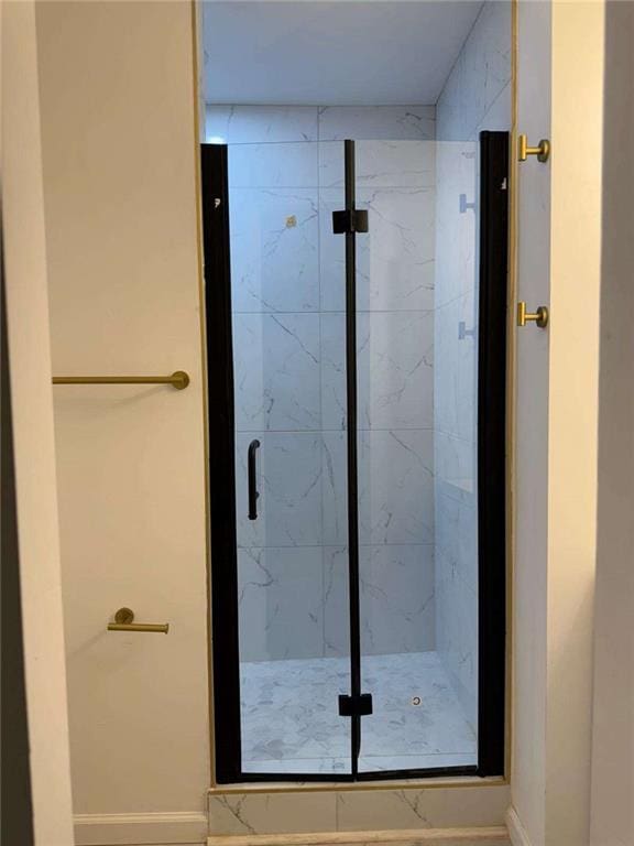 bathroom featuring a marble finish shower and baseboards